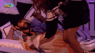 a man is laying on a bed with a woman standing next to him and the words sahara live channel on the bottom