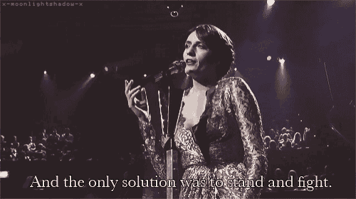 a woman singing into a microphone with a caption that says and the only solution was to stand and fight