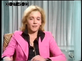 a woman in a pink jacket is sitting at a desk with a time stamp of 00:27:45