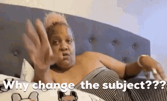 a woman is laying on a bed with her hand up and asking why change the subject .