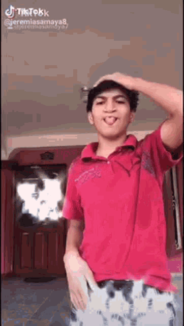 a young man in a red shirt is making a funny face .