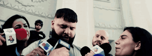 a man with a beard is being interviewed by a group of people holding microphones that say cnn