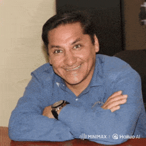a man wearing a blue shirt and a watch sits at a table