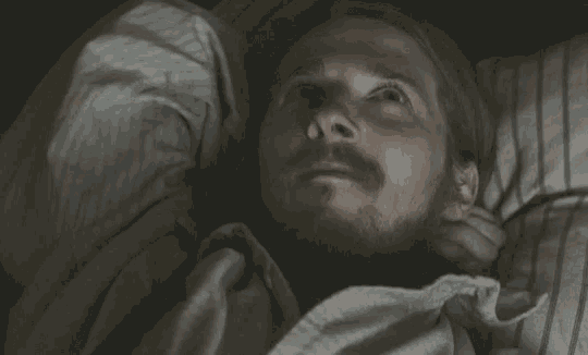 a man with a beard is laying on a bed