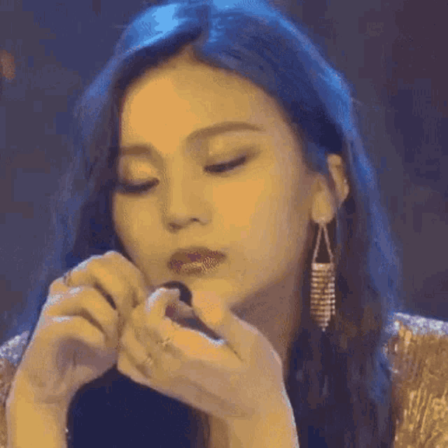 a woman is applying lipstick to her lips while wearing earrings .