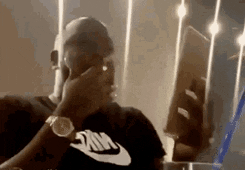 a man wearing a nike shirt is sitting in front of a mirror .