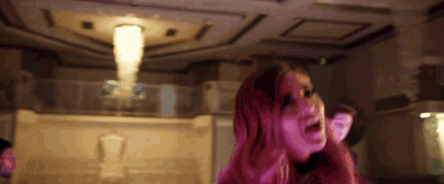 a woman with pink hair is dancing in a room with purple lights