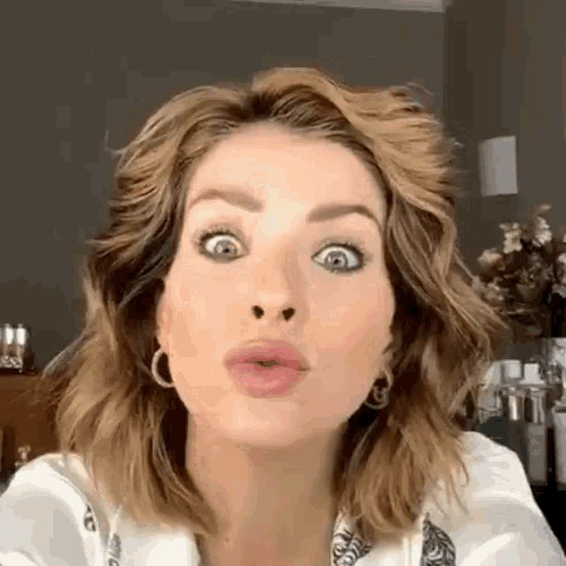a woman is making a funny face with her mouth open and a surprised look on her face .