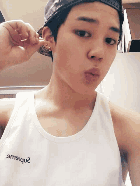 a young man wearing a hat and a white tank top that says 2nb6w2 on it
