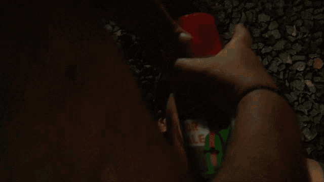 a man laying on the ground with his eyes closed and a hand holding a can