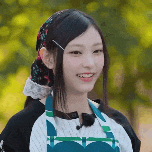 a woman wearing an apron and a headband smiles at the camera