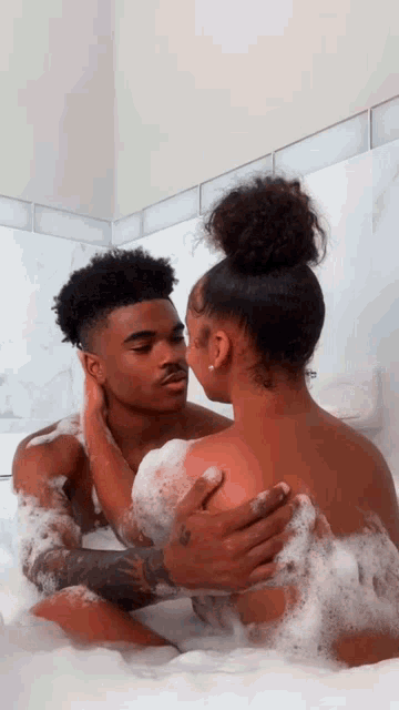 a man and woman are kissing in a bathtub filled with foam