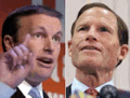 two men are standing next to each other in front of a microphone and one is pointing at the camera .