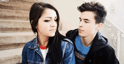 a boy and a girl are sitting next to each other on the stairs .
