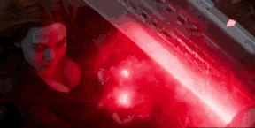 a woman is standing next to a red light that is coming out of a machine .