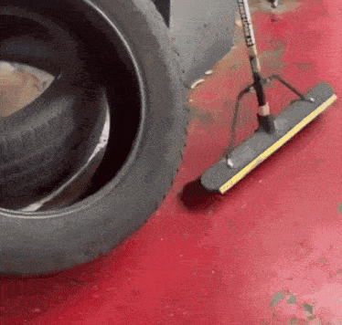 a tire and a broom on a red floor with a sticker that says ' johnson ' on it