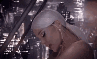 ariana grande is wearing a white ponytail and earrings in a video .
