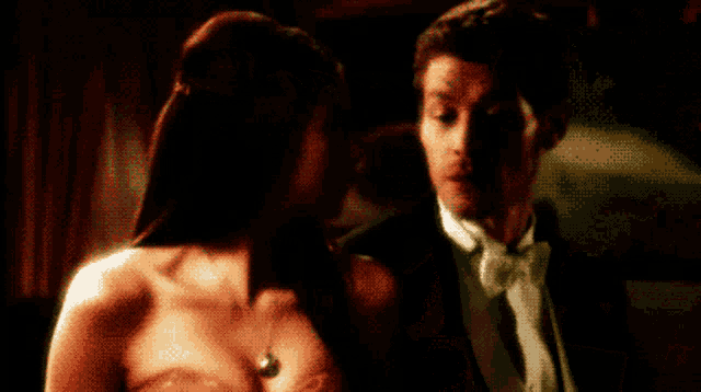 a man in a tuxedo and a woman in a strapless dress are looking at each other