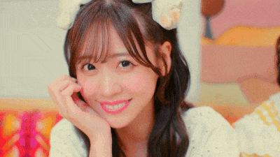 a young girl with a flower in her hair is smiling and looking at the camera .