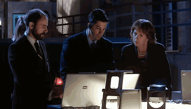 two men and a woman are looking at a laptop that says thinkpad
