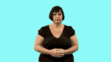 a woman in a black shirt is making a gesture with her hands against a blue background .