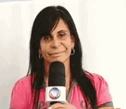 a woman in a pink shirt is holding a microphone in her hand