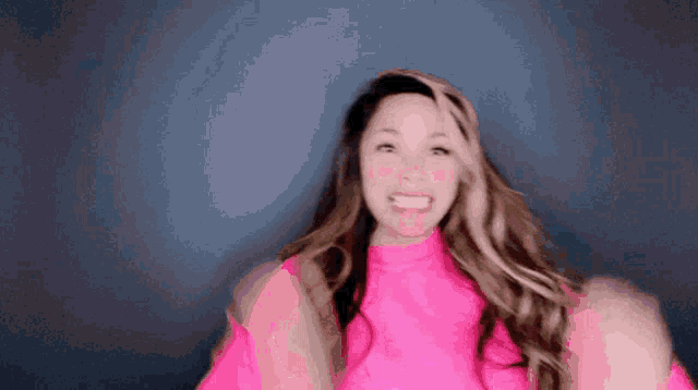 a woman is wearing a pink sweater and making a funny face