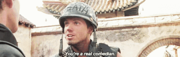 a man in a helmet is talking to another man and says " you 're a real comedian "