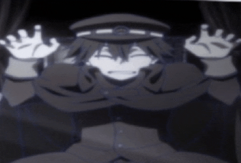a man in a hat is sitting in a dark room with his hands up in the air