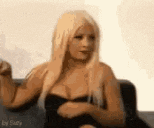 a woman with blonde hair is sitting on a couch .
