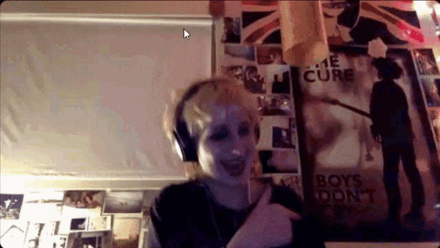 a woman wearing headphones stands in front of a poster that says boys don t cry