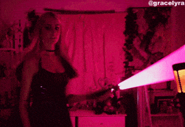 a woman in a black dress is holding a pink light sword