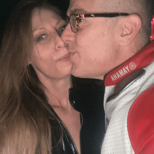 a man kissing a woman wearing a red jacket that says ahamay