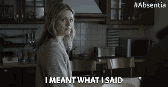 a woman sitting at a table with the words " i meant what i said " next to her