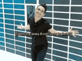 a man in a black shirt is dancing in front of a blue and white tiled wall