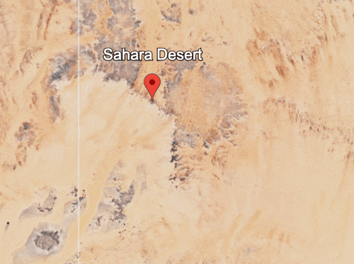 an aerial view of the sahara desert with a red pin pointing the location