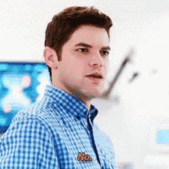 a man wearing a blue plaid shirt with a no sticker on his shirt .