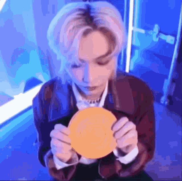 a man with blonde hair is holding a yellow plate in his hands .