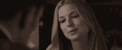 a woman is making a funny face while looking at a man in a dark room .