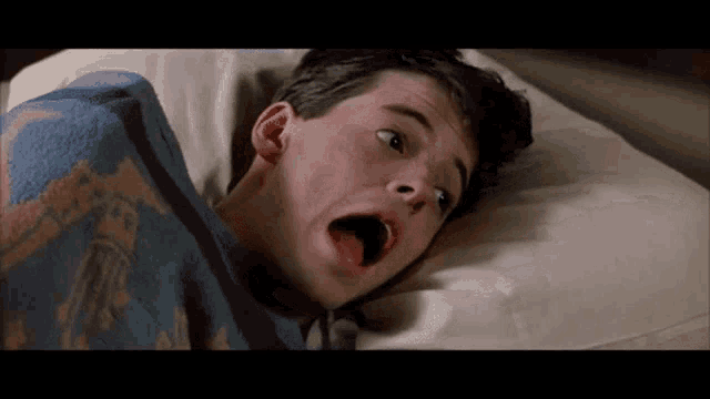 a man laying in bed with his mouth open