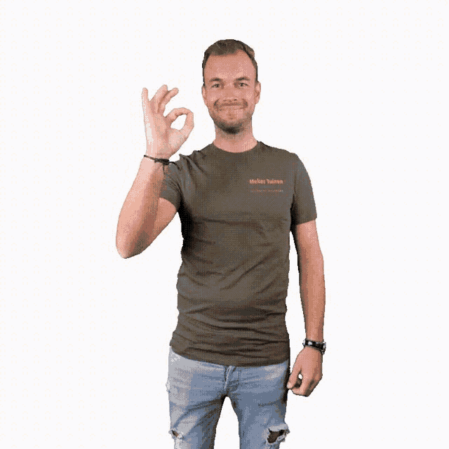 a man in a green t-shirt and blue jeans is giving an ok sign