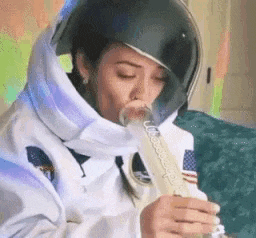 a woman in an astronaut costume is blowing a bong .