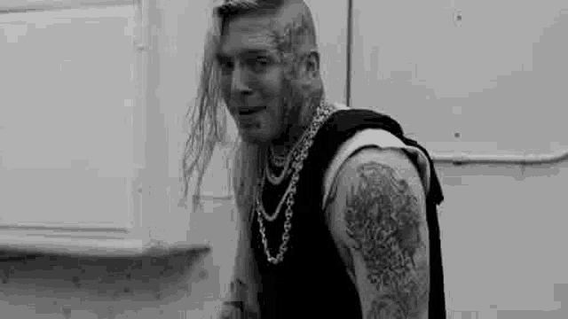 a black and white photo of a man with a lot of tattoos on his body .