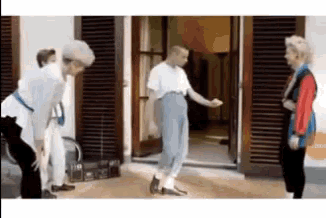a group of people are standing in front of a door talking to each other