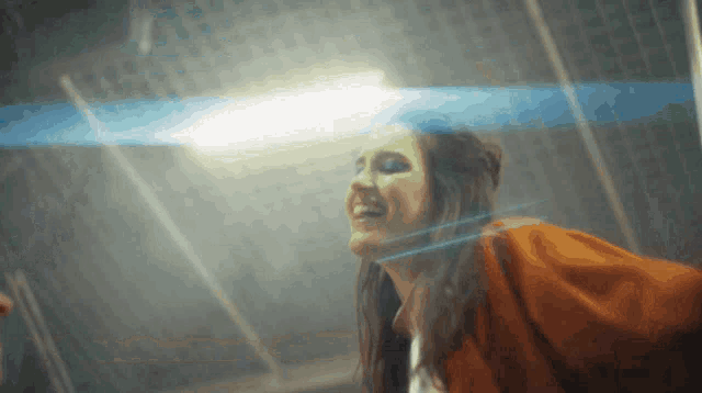 a woman in an orange jacket is looking up at something