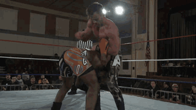 two wrestlers in a ring with one wearing number 12