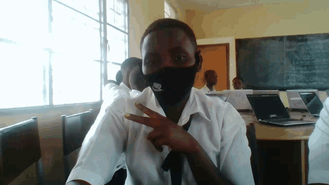 a man wearing a nike face mask giving the peace sign