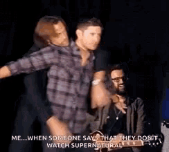 a man in a plaid shirt is dancing on a stage while another man watches .