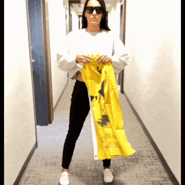 a woman wearing sunglasses holds up a yellow flag that says ' on a sunny day ' on it