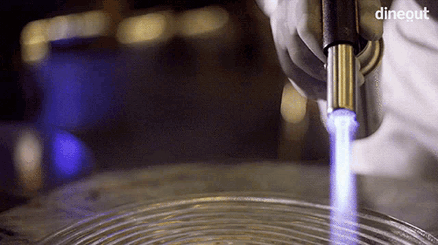 a close up of a person using a torch with the word dineout in the upper right corner
